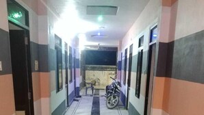 A hallway with a motorcycle parked at the end, doors on both sides, and a tiled floor. - HOLKAR SEVA SADAN (Mathura)