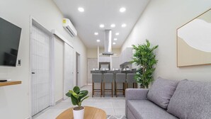 A modern living room with a grey sofa, a wooden coffee table, and a potted plant. - 2 BD Suite w/ Balcony, Gym, Rooftop Pool, Jacuzzi (Playa del Carmen)