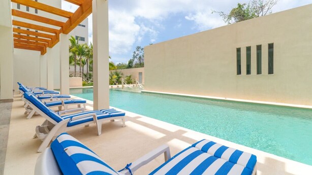 A poolside area with lounge chairs and a clear view of the pool. - 2 BD Suite w/ Balcony, Gym, Rooftop Pool, Jacuzzi (Playa del Carmen)