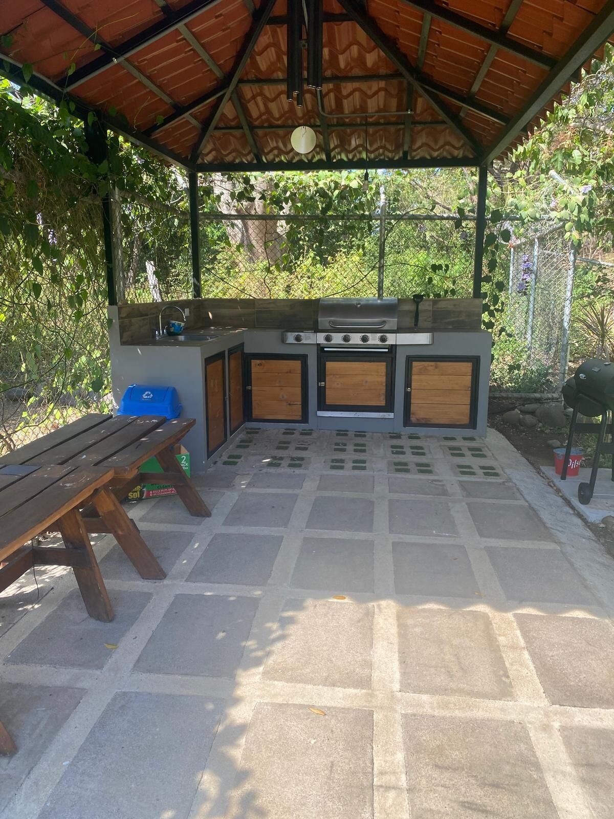 Un área de cocina al aire libre con una parrilla, un fregadero y una mesa de madera.