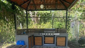 An outdoor kitchen area with a grill, sink, and a wooden table. - Coco Beach Costa Rica, 2 Bedrm 2 Bath condo with beautiful outdoor space (Guanacaste Province)