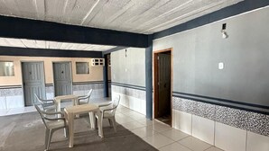 A hallway with a tiled floor, a table with chairs, and doors. - APART HOTEL ROCHA (Porto Velho)