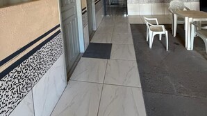 A corridor with doors, a tiled floor, and a seating area with chairs and a table. - APART HOTEL ROCHA (Porto Velho)