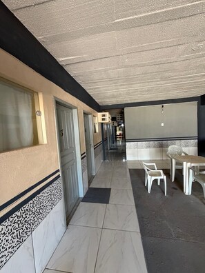A corridor with doors, a tiled floor, and a seating area with chairs and a table. - APART HOTEL ROCHA (Porto Velho)