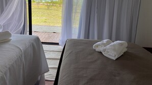 A room with two beds, each with a white towel, and sheer curtains allowing a view of the outdoors. - Aponem Spa Pousada (Prado)