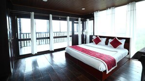 A spacious bedroom with a large bed, wooden flooring, and a balcony with a railing. - Coorg Tree House (Madikeri)