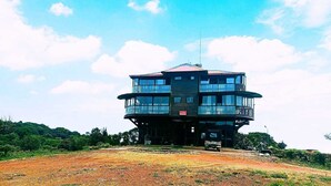 A multi-story building with a central tower, surrounded by greenery. - Coorg Tree House (Madikeri)