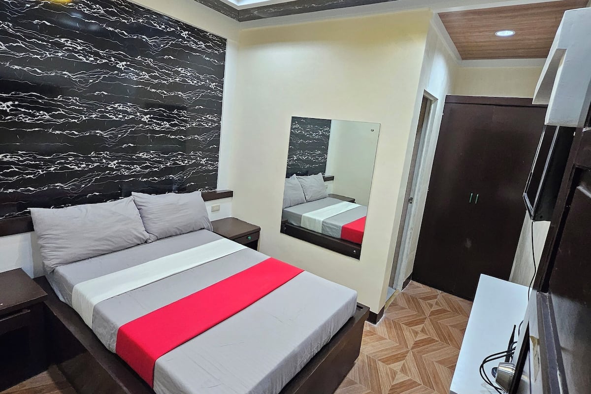 A modern bedroom with a large bed, a mirror, and a wardrobe.