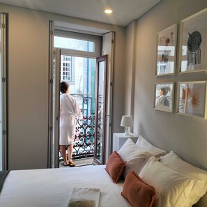 A hotel room with a bed, a nightstand, a lamp, and a balcony door. - Bellu Studios & Suites   (Braga)