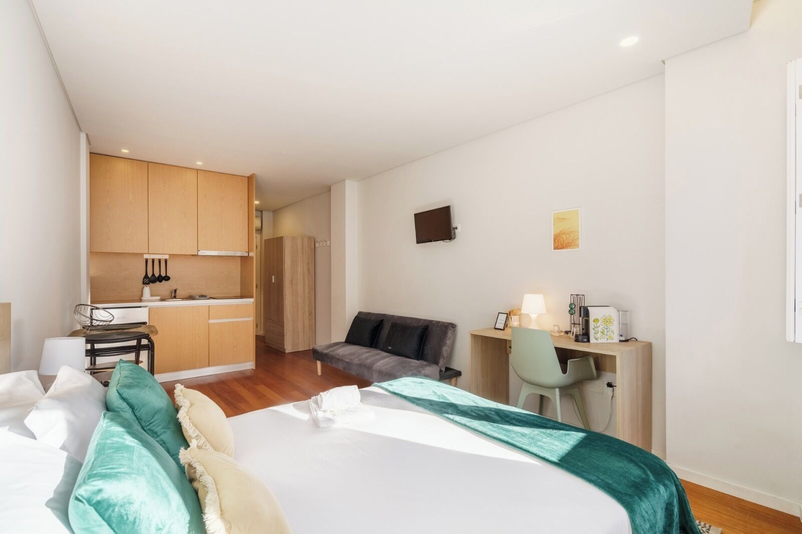 Ein modernes Hotelzimmer mit einem großen Bett, einem Schreibtisch, einer Couch und einer Küchenzeile.