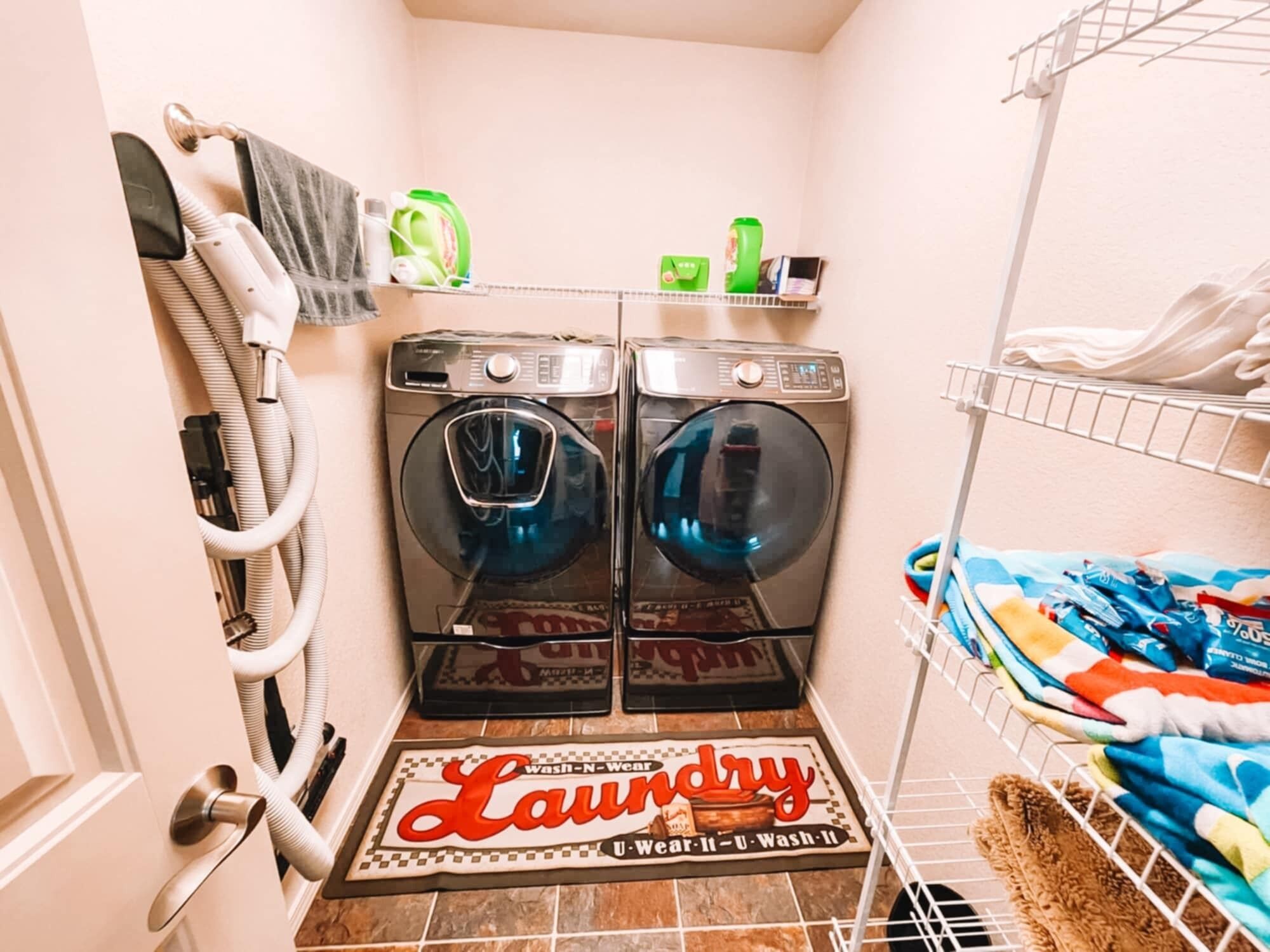 A laundry area with two front-loading washing machines, a drying rack, and a towel rack.