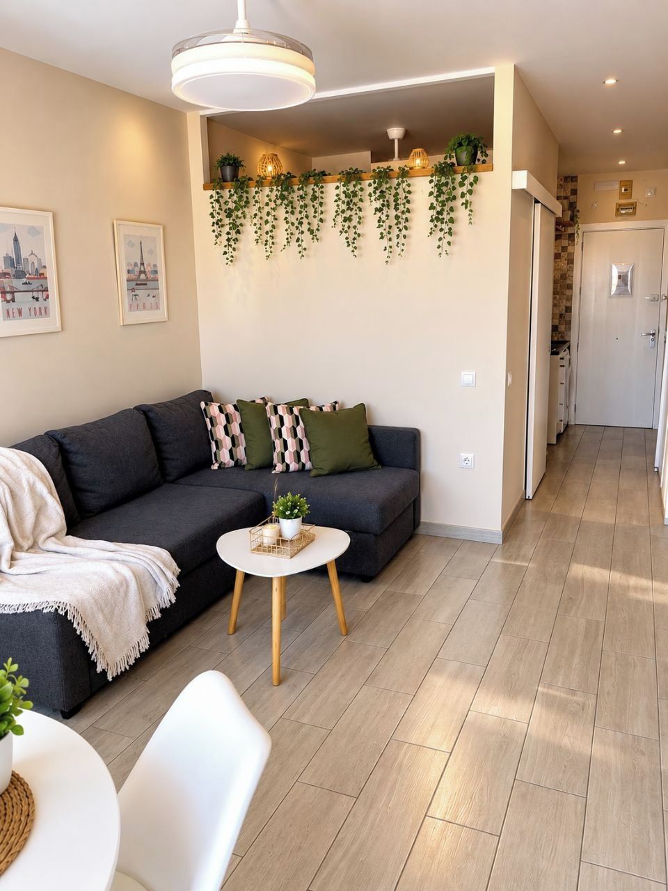 A modern living room with a sofa, a small round table, and a hanging plant arrangement.
