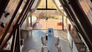 Una habitación tipo tienda de campaña con vista a una terraza de madera y asientos al aire libre.