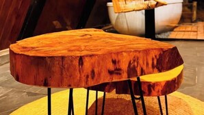 Una mesa de madera con un diseño único, que presenta una base circular y patas negras.
