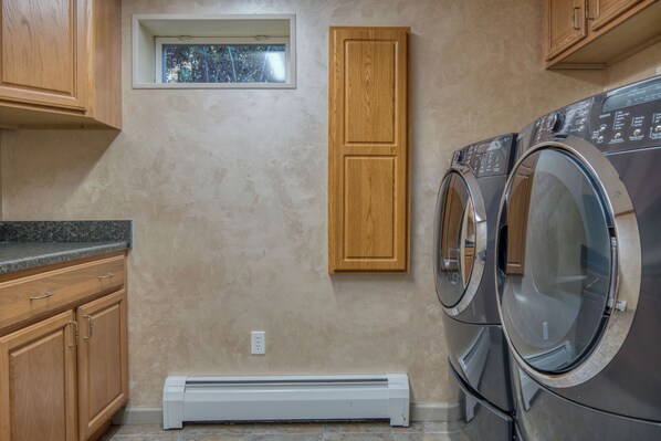 A laundry room with wooden cabinets, a built-in washer and dryer, and a small window.