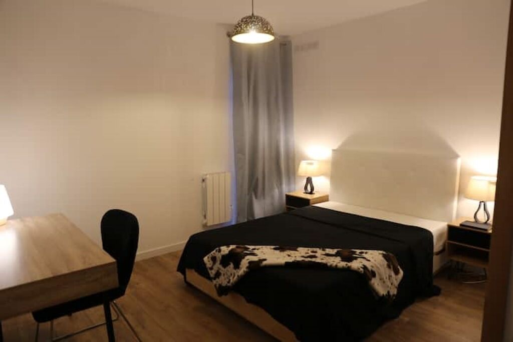 Een slaapkamer met een bed, een bureau en een stoel.