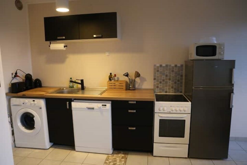 Cocina compacta con lavadora, lavavajillas, microondas y horno.