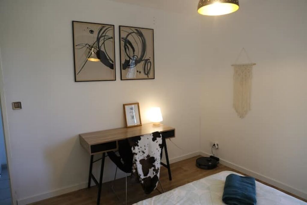 Un dormitorio con una cama, un escritorio y dos cuadros abstractos en la pared.