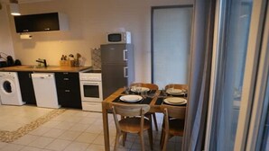 Ett kompakt kök med en matplats, inklusive mikrovågsugn, ugn och tvättmaskin.
