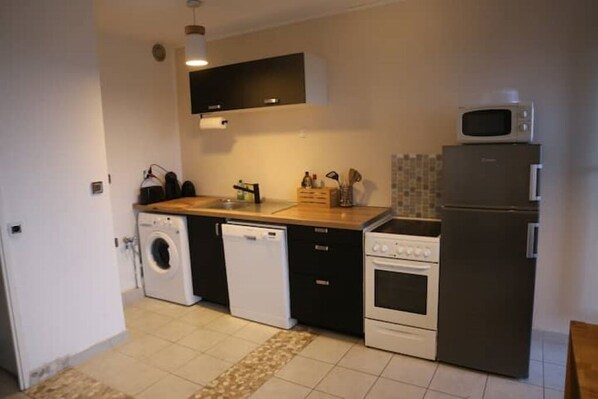A compact kitchen with a washing machine, dishwasher, oven, and microwave.