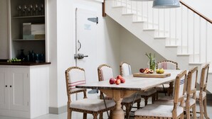 A dining area with a wooden table and chairs, a staircase, and pendant lights. - Shalmar Hollow - Rock - sleeps up to 12 - perfect for family groups (Rock)