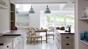 A bright kitchen with white cabinetry, a wooden dining table, and two pendant lights. - Shalmar Hollow - Rock - sleeps up to 12 - perfect for family groups (Rock)
