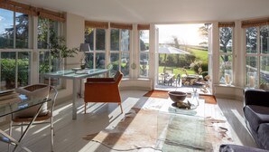 A spacious room with large windows, a glass table, a leather sofa, and a dining area with outdoor views. - Shalmar Hollow - Rock - sleeps up to 12 - perfect for family groups (Rock)