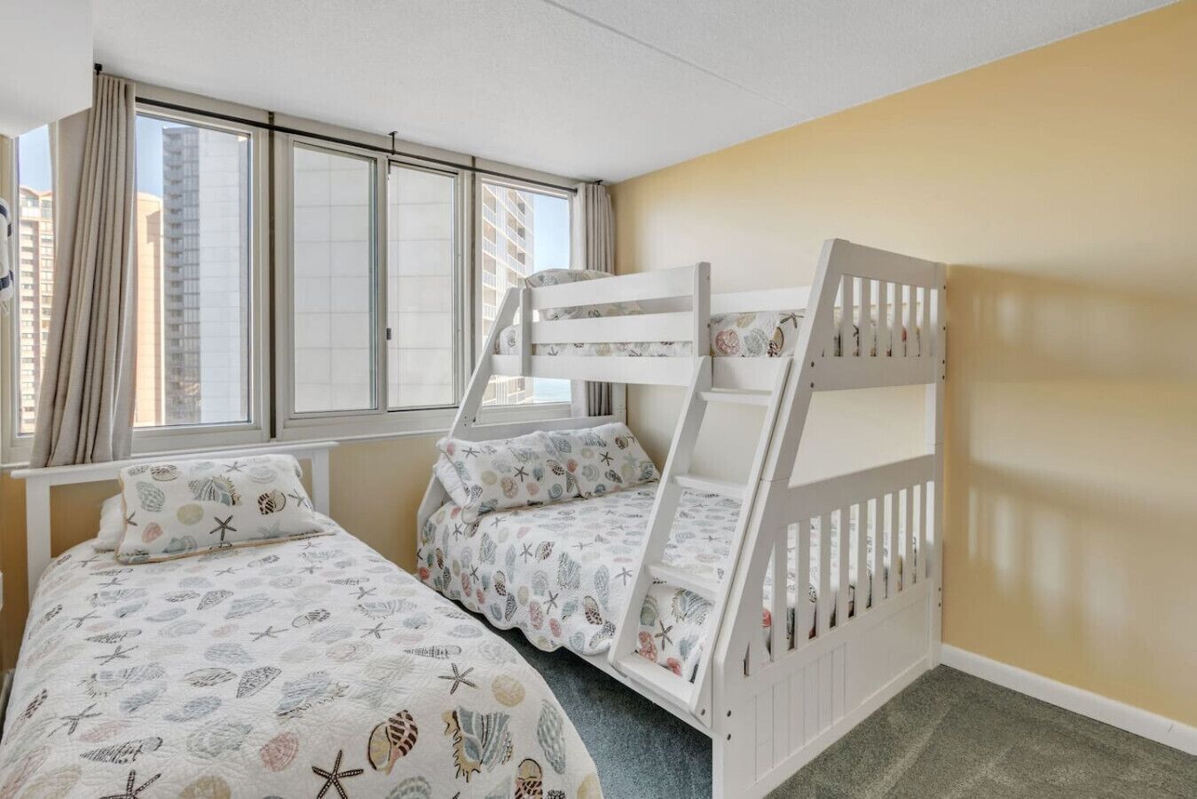 A room with a bunk bed, a single bed, and a window with curtains.