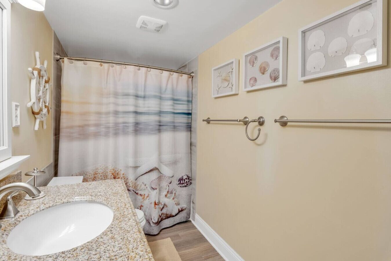 Une salle de bain avec un lavabo, un meuble-lavabo, un rideau de douche et des tableaux encadrés au mur.