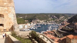 A coastal town with a historic fort, marina with boats, and residential buildings. - A Rossa Location (Conca)