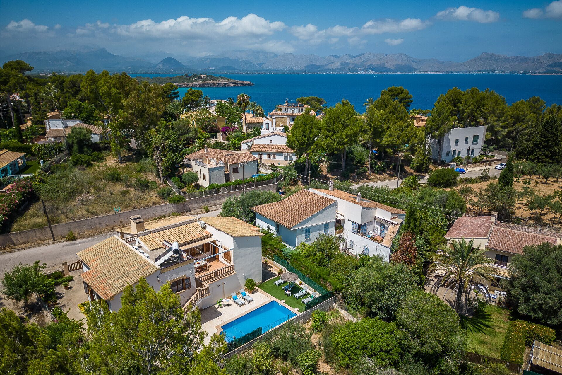 Uma área residencial costeira com casas, piscina e vista para o mar.