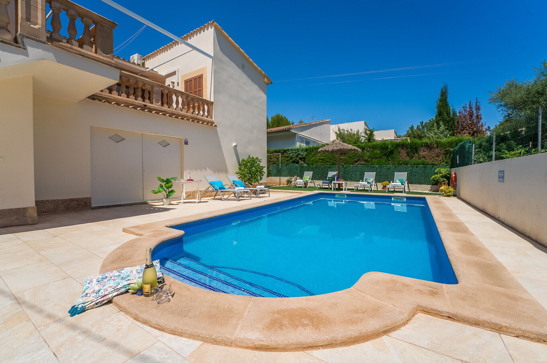 Ein Swimmingpool mit Liegestühlen und einem Tisch, umgeben von einem weißen Gebäude mit Balkon.