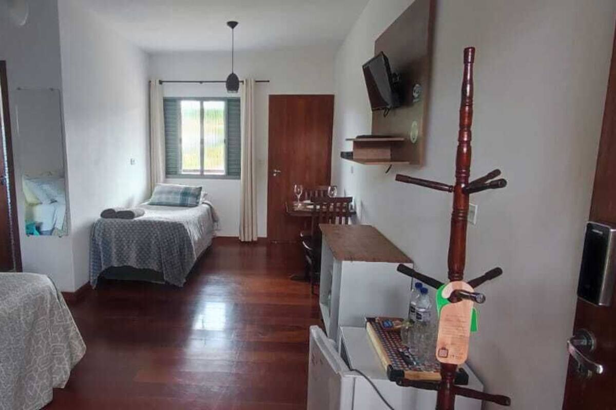Ein Hotelzimmer mit einem Bett, einem Schreibtisch, einem Stuhl, einem Fernseher, einem Holzgestell und einem Fenster.