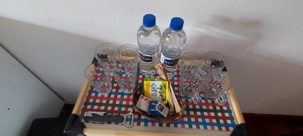 Un plateau contenant des bouteilles d’eau, des verres, une boîte de mouchoirs et un flacon de gel hydroalcoolique.