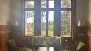 Une pièce avec une grande fenêtre, un canapé, deux fauteuils et une petite table.