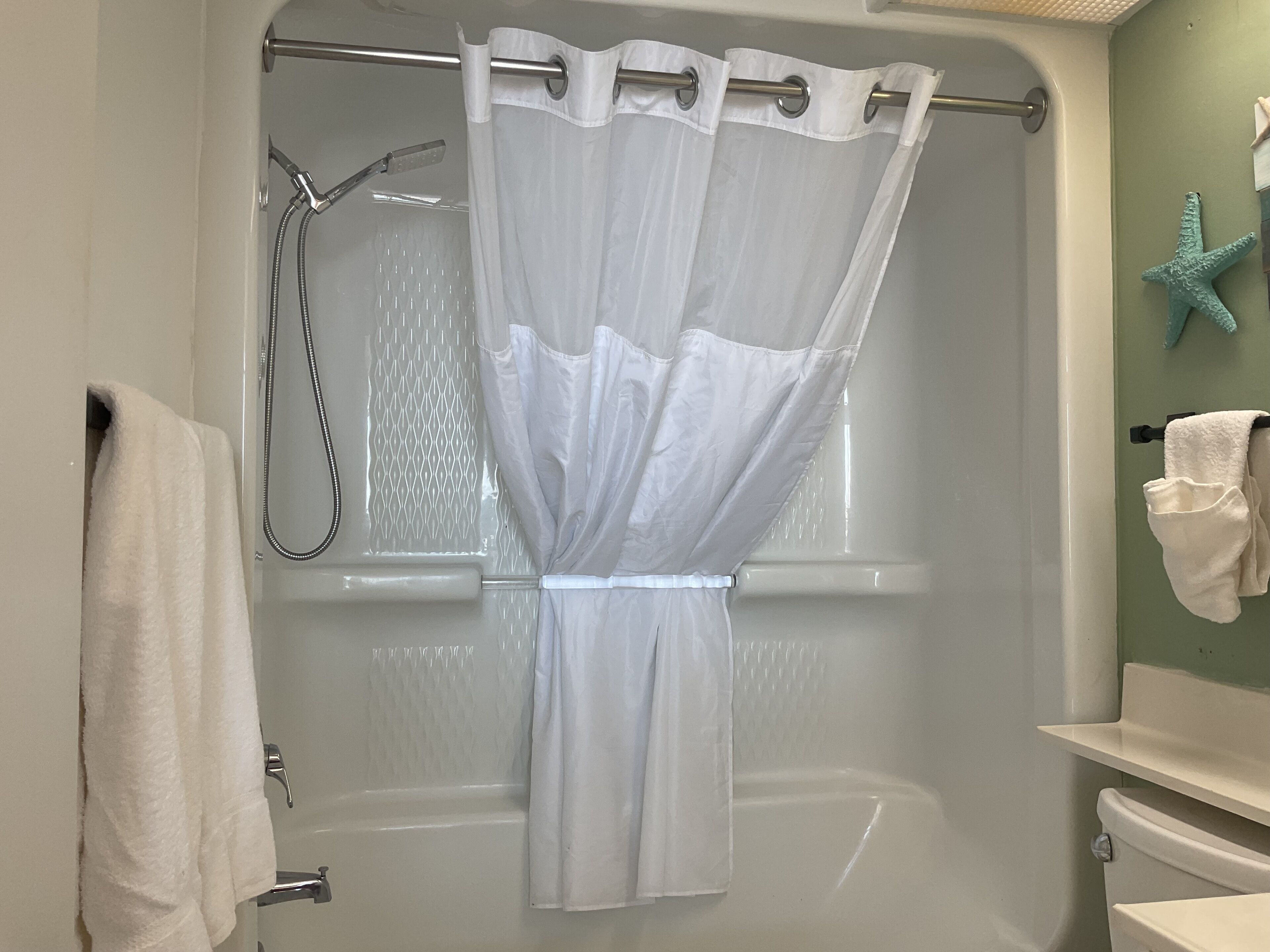 A bathroom with a shower curtain, a bathtub, and a toilet.