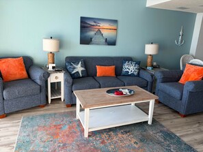 A living room with a sofa set, a coffee table, and a painting on the wall. - Seawatch Resort 2 BDR (Myrtle Beach)
