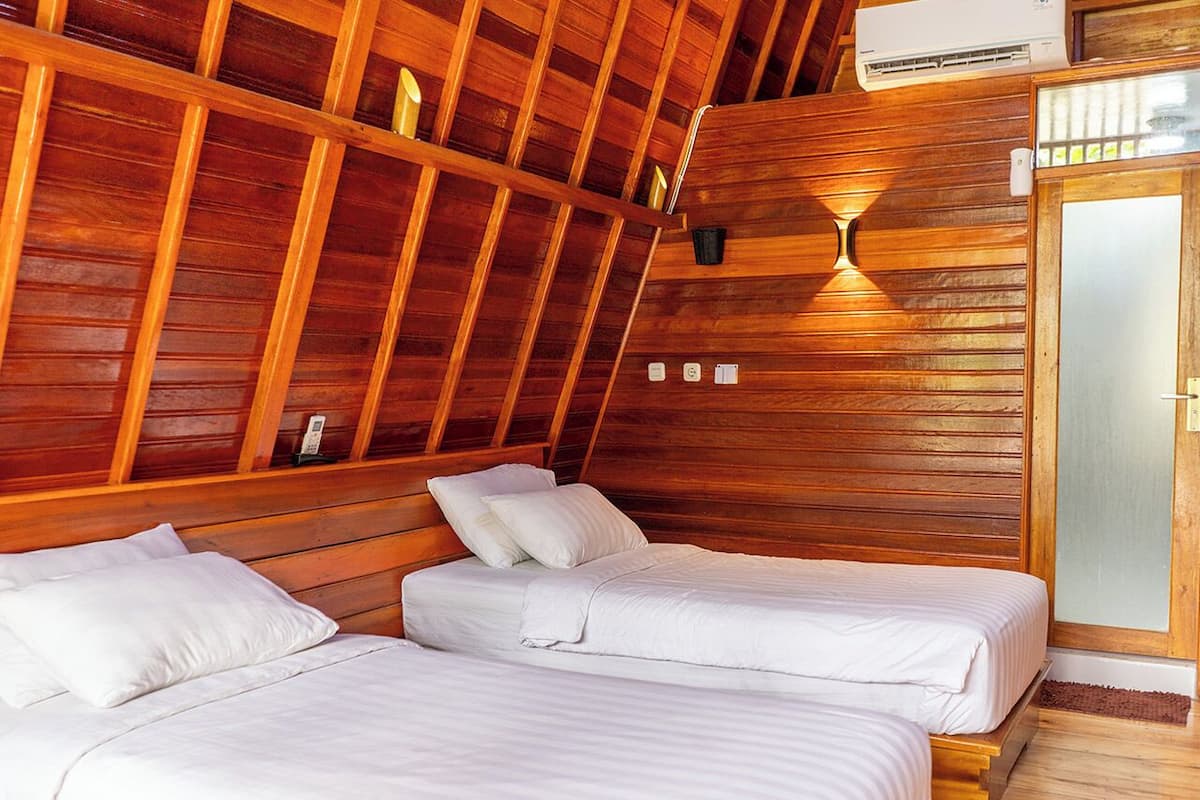A room with two beds, wooden walls, and an air conditioning unit.