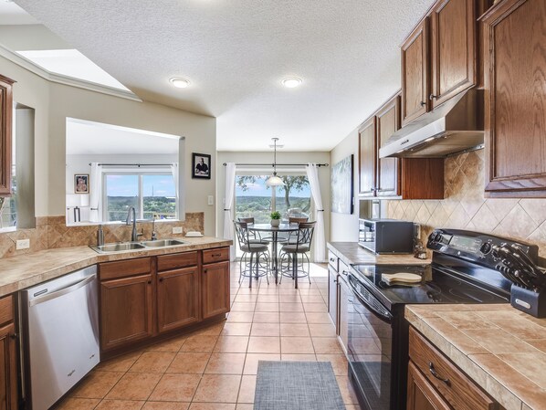 Una cocina moderna con lavavajillas, estufa y comedor con vistas.