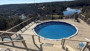 Une terrasse en bois avec une piscine, entourée d’une rambarde en métal.