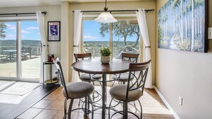 Un coin repas avec une table et des chaises, une vue dégagée grâce à de grandes fenêtres et un tableau accroché au mur.
