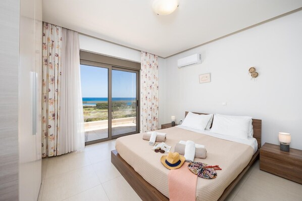 A bedroom with a large bed, a view of the sea, and a balcony. - Villa Blue Wave Tria (Rhodes)