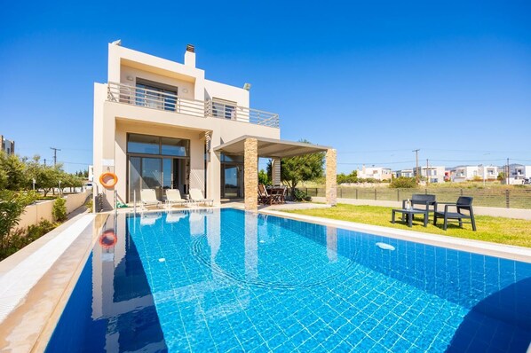 A modern two-story house with a swimming pool, outdoor seating, and a clear view of the surrounding area. - Villa Blue Wave Tria (Rhodes)
