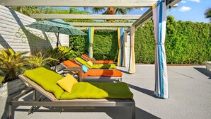 Un espace aménagé au bord de la piscine, avec des chaises longues, des parasols et une structure en forme de pergola.
