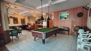 Een pooltafel in een kamer met een rode bakstenen muur, een schilderij en een klok.