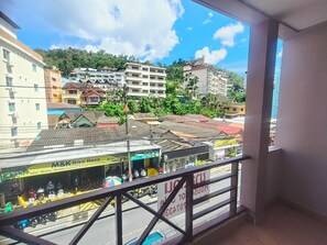A view from a balcony overlooking a street with buildings, a bike rental shop, and a sign for a hotel. - Bonanza Patong Hotel (Patong)