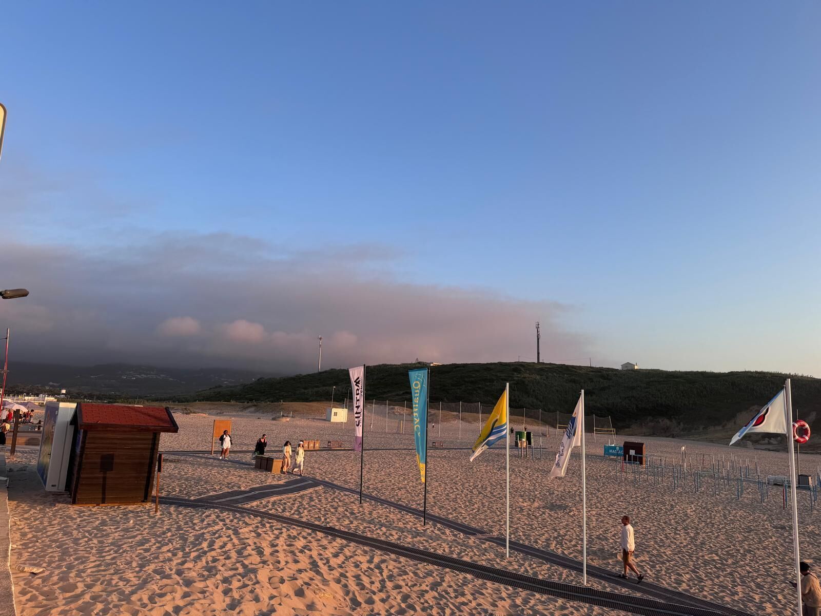 Ein Strand mit einer kleinen Holzhütte, Flaggen und einem Rettungsring.