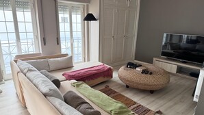 A modern living room with a sofa, ottoman, and television. - Atlantic Views Sintra Guest House (Sintra)