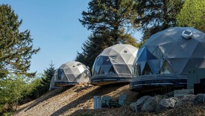 Three geodesic dome structures on a hillside with a clear sky. - Two Capes Lookout (Cloverdale)