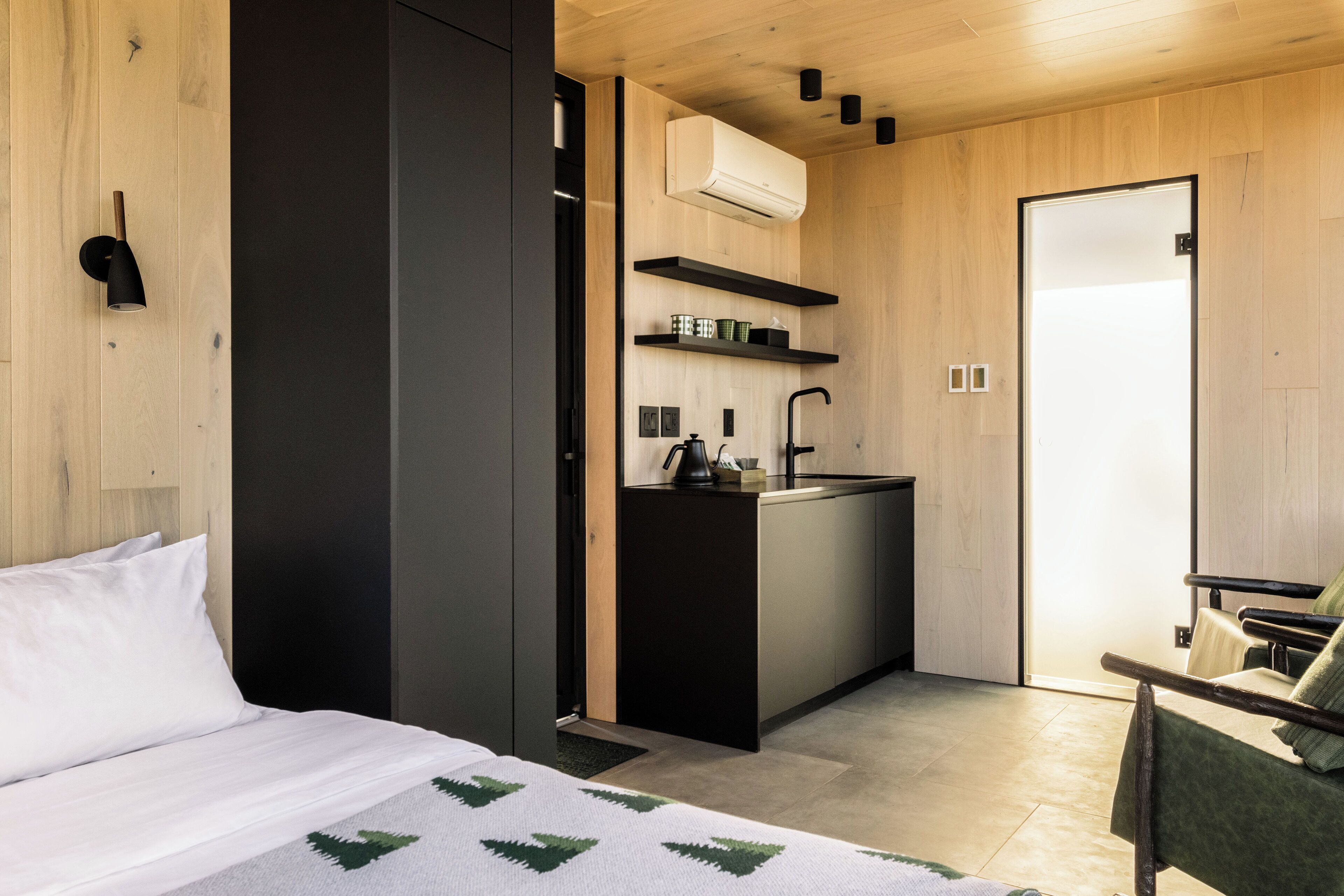 Una habitación de hotel compacta con cama, kitchenette pequeña y zona de estar.